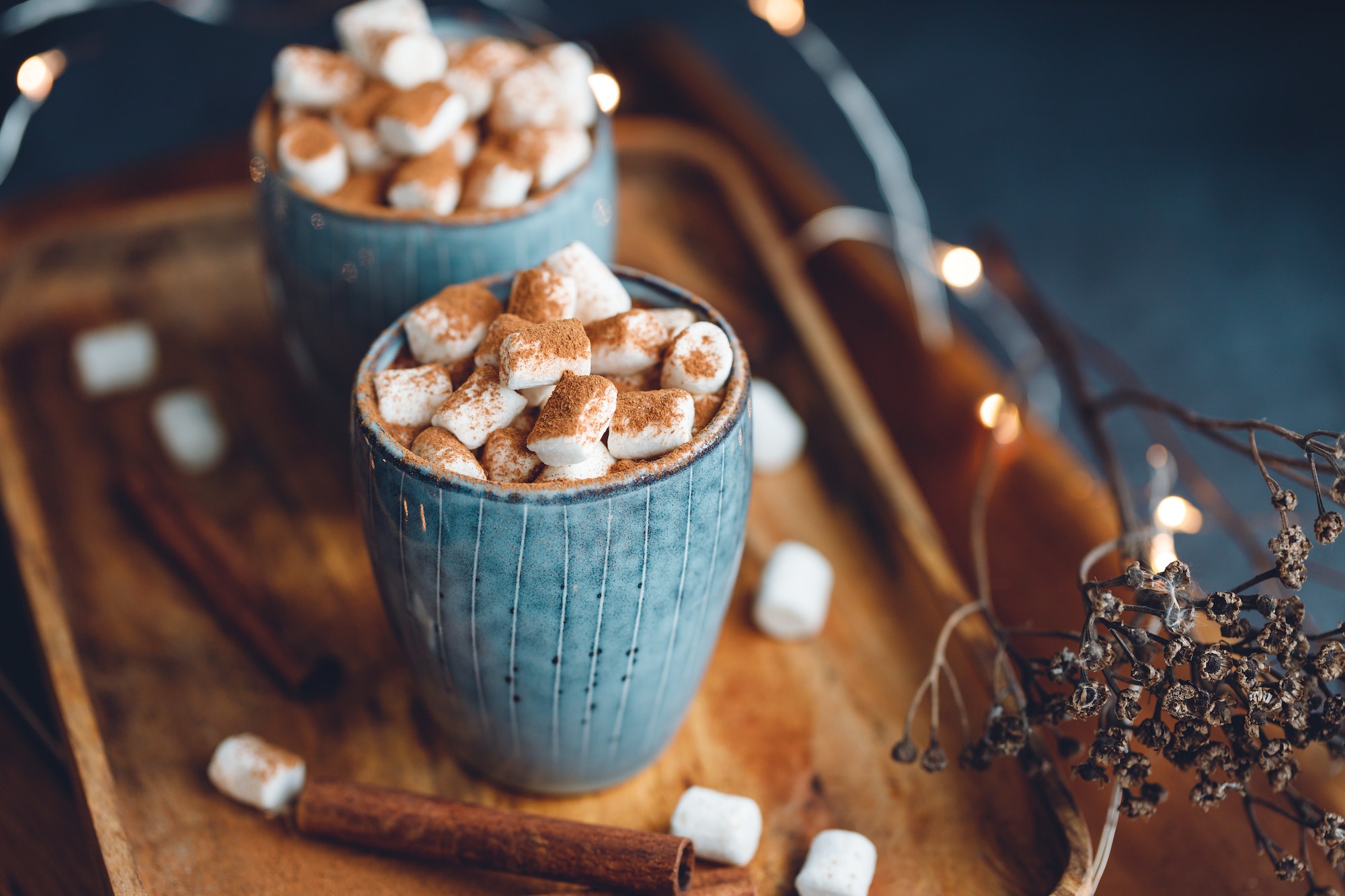 Hot chocolate with marshmallow and cinnamon in a blue ceramic cups on a table.